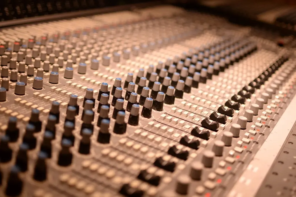 Warm tungsten light across a bank of console faders