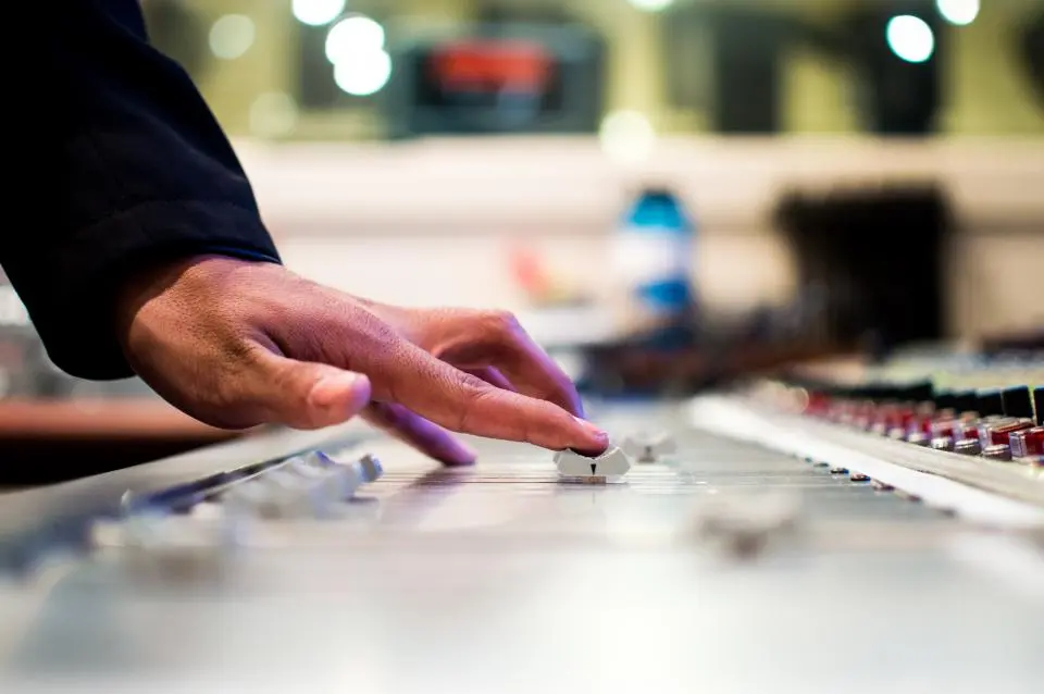 A hand pushing a single fader on a mixing desk